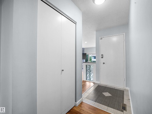 Entryway with wood-finish flooring, a white bi-fold closet, and a tiled landing - 7435 32 Avenue Nw, Edmonton, AB 