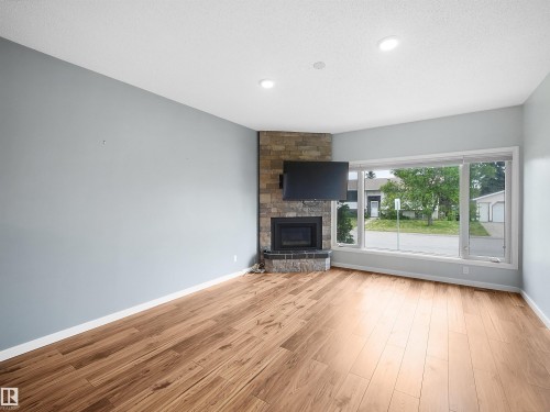 Wood-finish flooring, recessed lighting, and a stone-clad fireplace with hearth - 7435 32 Avenue Nw, Edmonton, AB 