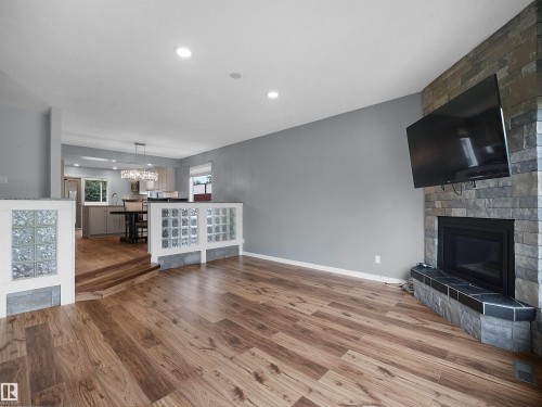 Wood-finish flooring, recessed lighting, stone-clad fireplace, glass block accent walls, and an open-concept design - 7435 32 Avenue Nw, Edmonton, AB 