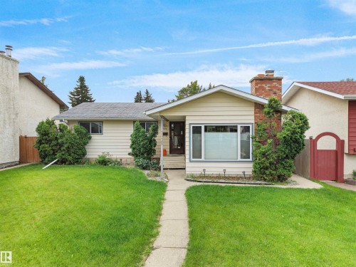 Ranch-style exterior with light-toned siding and a brick chimney - 7435 32 Avenue Nw, Edmonton, AB 