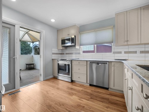 Wood-finish flooring, stainless steel appliances, light-toned cabinetry, and granite countertops - 7435 32 Avenue Nw, Edmonton, AB 