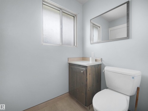 Sliding window, vanity with a white countertop, wall-mounted mirror, and tile flooring - 7435 32 Avenue Nw, Edmonton, AB 