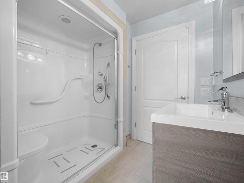 Walk-in shower with integrated seating, grab bars, and a clear glass enclosure - 7435 32 Avenue Nw, Edmonton, AB 