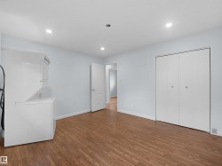 Wood-finish flooring throughout, recessed lighting, and bright white bi-fold closet doors - 