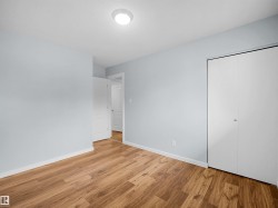 Wood-finish flooring, light blue wall paint, flush mount ceiling light, white bi-fold closet doors, and white interior door - 
