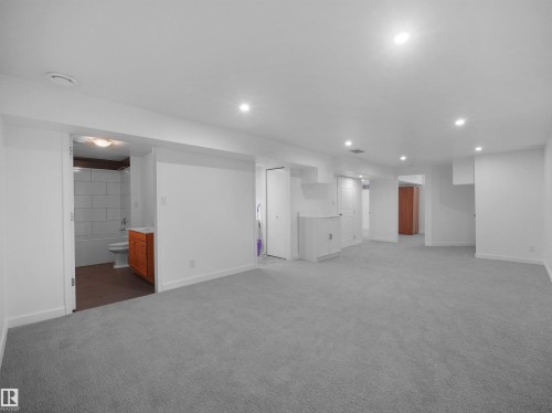 Expansive carpeted area with recessed lighting, white walls, and built-in white cabinetry - 7435 32 Avenue Nw, Edmonton, AB 