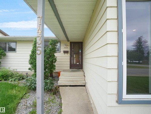 Cream-colored horizontal siding with a dark brown entry door - 7435 32 Avenue Nw, Edmonton, AB 
