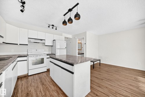 White cabinetry with dark hardware, stone-finish countertops, and wood-finish flooring - #30 300 Hooper Cr Nw, Edmonton, AB 