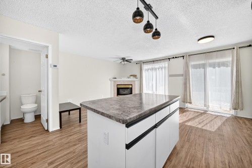 Kitchen island with a stone-finish countertop, white cabinetry, and matte black drawer pulls - #30 300 Hooper Cr Nw, Edmonton, AB 