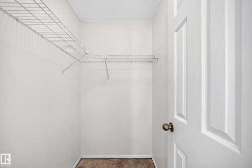 Built-in wire shelving, white paneled door, and textured ceiling - #30 300 Hooper Cr Nw, Edmonton, AB 