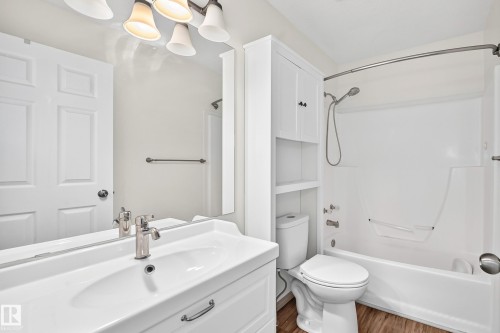 White vanity with integrated sink, brushed nickel faucet, full-width mirror, and multi-light fixture - #30 300 Hooper Cr Nw, Edmonton, AB 