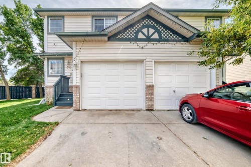 Two-story exterior with siding, two garage doors, and brick accents - #30 300 Hooper Cr Nw, Edmonton, AB 