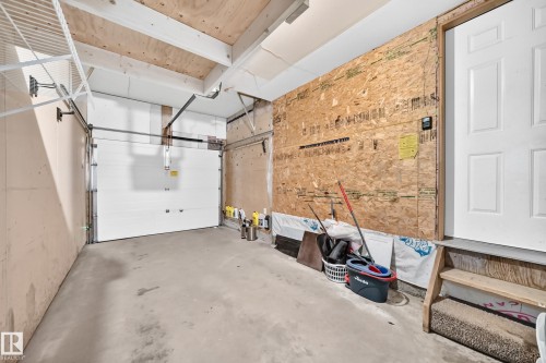 Concrete flooring with a white overhead garage door and exposed wood beams - #30 300 Hooper Cr Nw, Edmonton, AB 