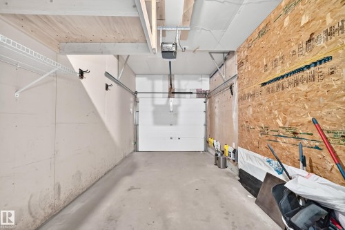 Garage space with a concrete floor, built-in shelving, and a paneled garage door - #30 300 Hooper Cr Nw, Edmonton, AB 