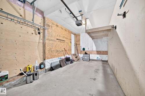 Concrete flooring with a built-in overhead storage rack, wood-panel walls, and an overhead garage door opener - #30 300 Hooper Cr Nw, Edmonton, AB 