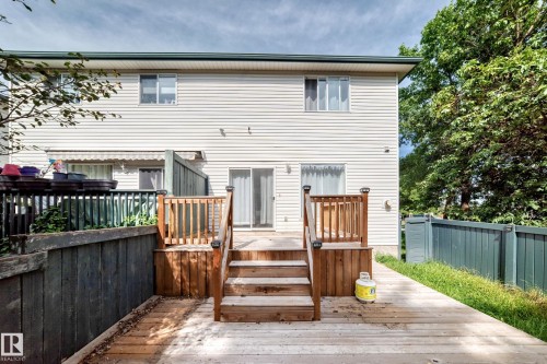 Expansive wood deck with stairs and railings, featuring a privacy fence and mature trees - #30 300 Hooper Cr Nw, Edmonton, AB 