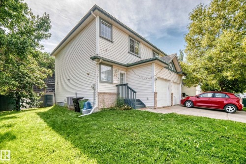 Two-story exterior with light-colored siding, double garage, and a concrete driveway - #30 300 Hooper Cr Nw, Edmonton, AB 