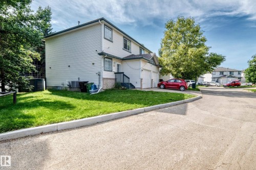 Two-story exterior with light-colored siding, dark trim, and a two-car garage - #30 300 Hooper Cr Nw, Edmonton, AB 