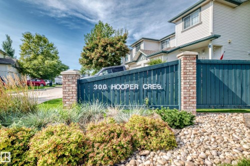 Exterior siding, brick column accents, decorative fencing, gravel landscaping, and established shrubbery - #30 300 Hooper Cr Nw, Edmonton, AB 