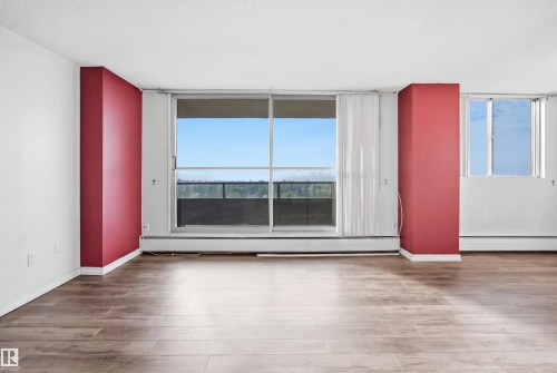 Wood-finish flooring throughout, full-height sliding glass doors, white baseboards, and a bright interior with natural light - #1115 13910 Stony Plain Rd Nw, Edmonton, AB 