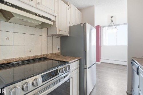 White cabinetry with brushed nickel hardware, light-toned backsplash tiling, and stone-finish countertops - #1115 13910 Stony Plain Rd Nw, Edmonton, AB 