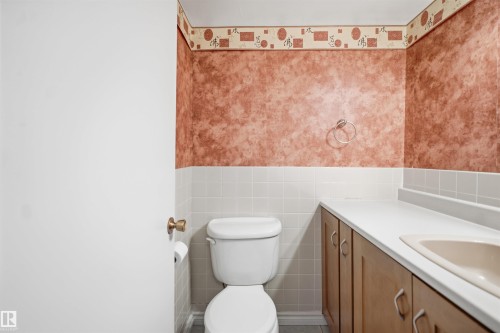 White toilet with a built-in vanity, light wood-finish cabinetry, and a white countertop with an integrated sink - #1115 13910 Stony Plain Rd Nw, Edmonton, AB 