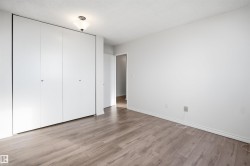 Wood-finish flooring with white baseboards, full-wall closet with bi-fold doors, white painted walls, and a ceiling-mounted light fixture - 