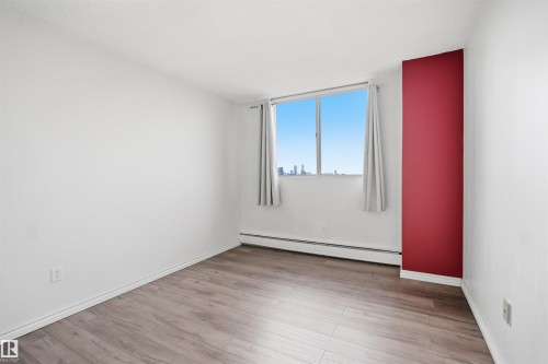 Room featuring wood-finish flooring, white painted walls, a red accent wall, and a large window - #1115 13910 Stony Plain Rd Nw, Edmonton, AB 