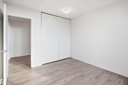 Wood-finish flooring, white walls, and a flush-mount ceiling light - 