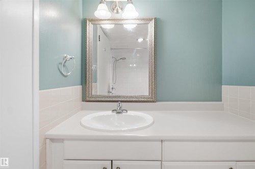 Vanity with an integrated sink, polished chrome faucet, and white cabinetry - #1115 13910 Stony Plain Rd Nw, Edmonton, AB 