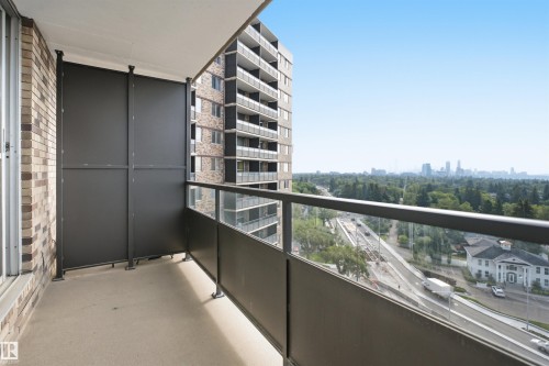 Balcony with glass railing, concrete flooring, and brick wall - #1115 13910 Stony Plain Rd Nw, Edmonton, AB 