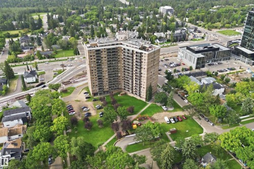 Multi-story building with multiple balconies, surrounded by green spaces and mature trees - #1115 13910 Stony Plain Rd Nw, Edmonton, AB 