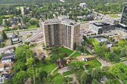 Multi-story building with multiple balconies, surrounded by green spaces and mature trees - 