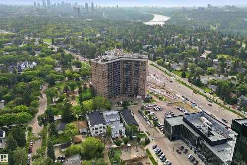 Expansive urban landscape featuring a high-rise building, a wide roadway, a distant river with a bridge, and numerous trees - #1115 13910 Stony Plain Rd Nw, Edmonton, AB 