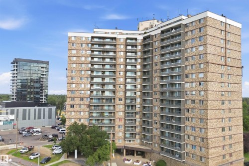 Multi-story residential building featuring a stone and stucco facade, individual balconies, and multiple windows - #1115 13910 Stony Plain Rd Nw, Edmonton, AB 