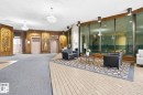 Lobby featuring decorative wood paneling, two elevators, and crystal chandeliers - #1115 13910 Stony Plain Rd Nw, Edmonton, AB 