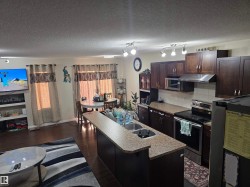 Kitchen featuring dark wood-finish cabinetry, stainless steel appliances, and a double basin sink - 