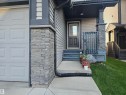 Exterior featuring horizontal siding, a paneled garage door, stacked stone accents, and a covered porch with dark wood-finish railing - 1474 33B Street Nw, Edmonton, AB 