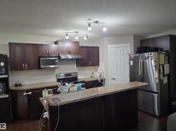 Kitchen featuring dark wood-finish cabinetry, granite-style countertops, and stainless steel appliances - 