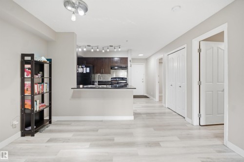 Wood-finish flooring, recessed lighting, track lighting, kitchen with dark cabinetry, and a peninsula countertop - #212 12035 22 Av Sw, Edmonton, AB 