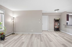 Light wood-finish flooring throughout, bright window, neutral painted walls, and a white paneled door - 