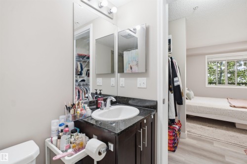Vanity with undermount sink, dark cabinetry, and integrated mirror - #212 12035 22 Av Sw, Edmonton, AB 