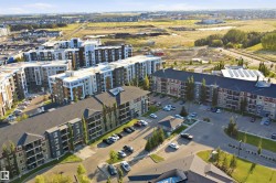 Residential buildings featuring multiple stories with balconies, surface parking, and a structured roofline - 
