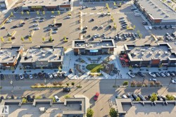 Expansive commercial center featuring multiple retail establishments, large parking areas, and a central pedestrian plaza with landscaping - 