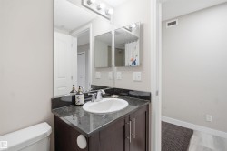 Dark wood-finish vanity with chrome hardware, an integrated basin, a dark stone-look countertop, and a wall-mounted mirror - 