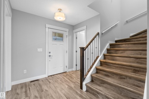 Entryway featuring wood-finish flooring, a white paneled door with decorative glass, and a semi-flush ceiling light - 2585 Pegasus Boulevard Nw, Edmonton, AB 