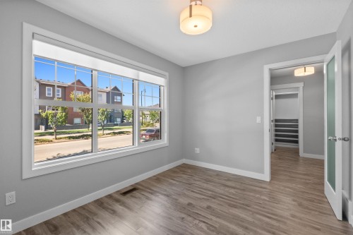 Expansive window with white trim, wood-finish flooring, light gray wall paint, and a semi-flush mount ceiling fixture - 2585 Pegasus Boulevard Nw, Edmonton, AB 