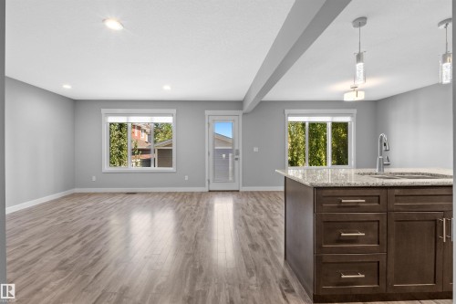 Open-concept living space with wood-finish flooring, recessed lighting, and ample natural light from multiple windows - 2585 Pegasus Boulevard Nw, Edmonton, AB 