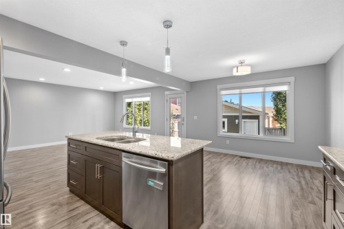 Kitchen island featuring a double-basin sink, stainless steel dishwasher, and granite countertop - 2585 Pegasus Boulevard Nw, Edmonton, AB 