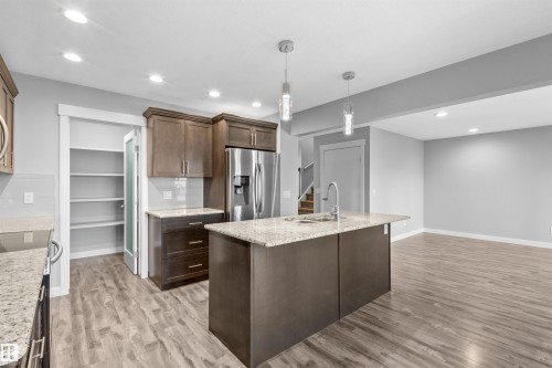 Kitchen featuring wood-finish flooring, recessed lighting, and a center island with pendant lights and a stainless steel sink - 2585 Pegasus Boulevard Nw, Edmonton, AB 
